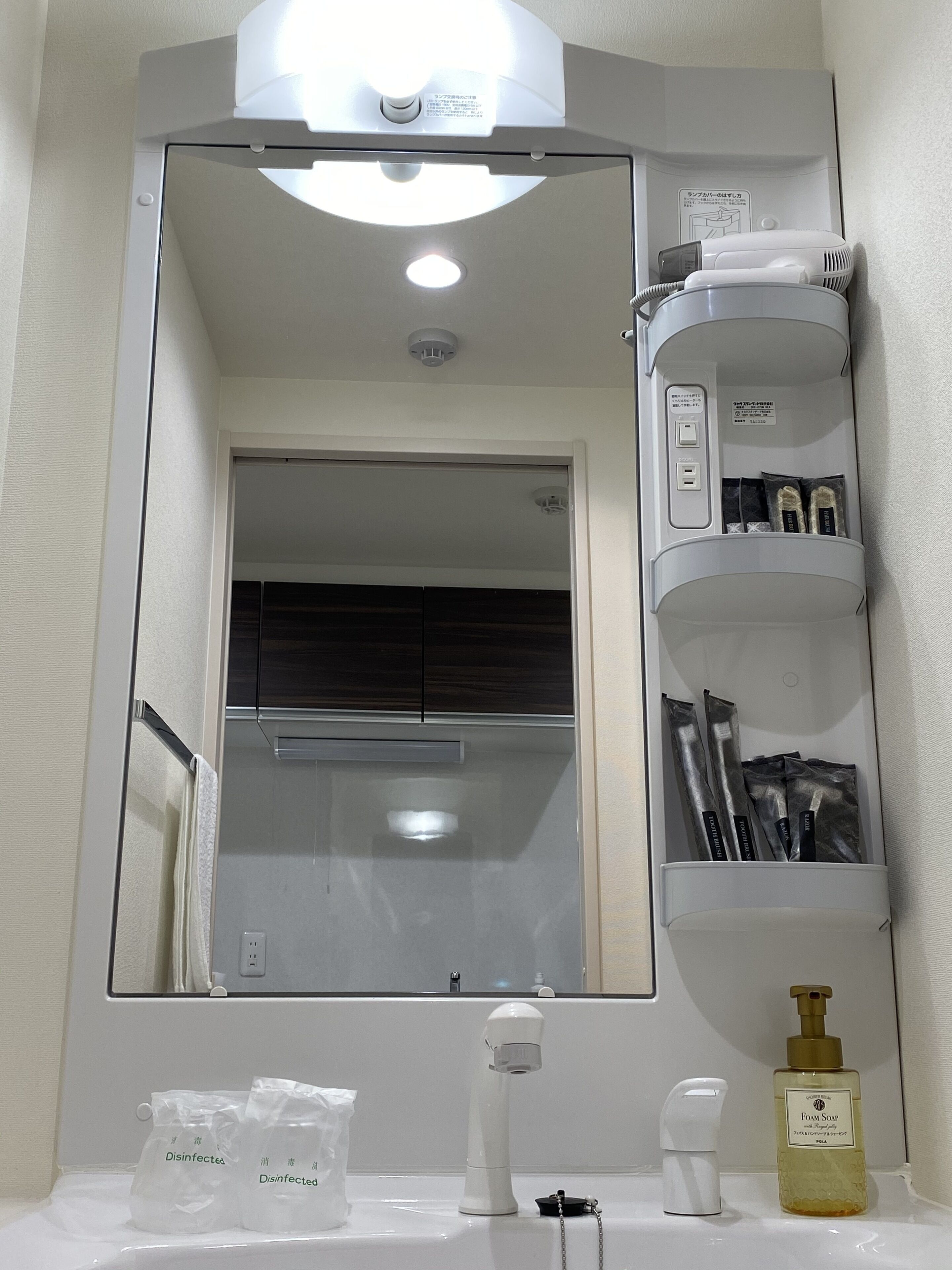 A bathroom with a mirror, sink, and shelves with toiletries.