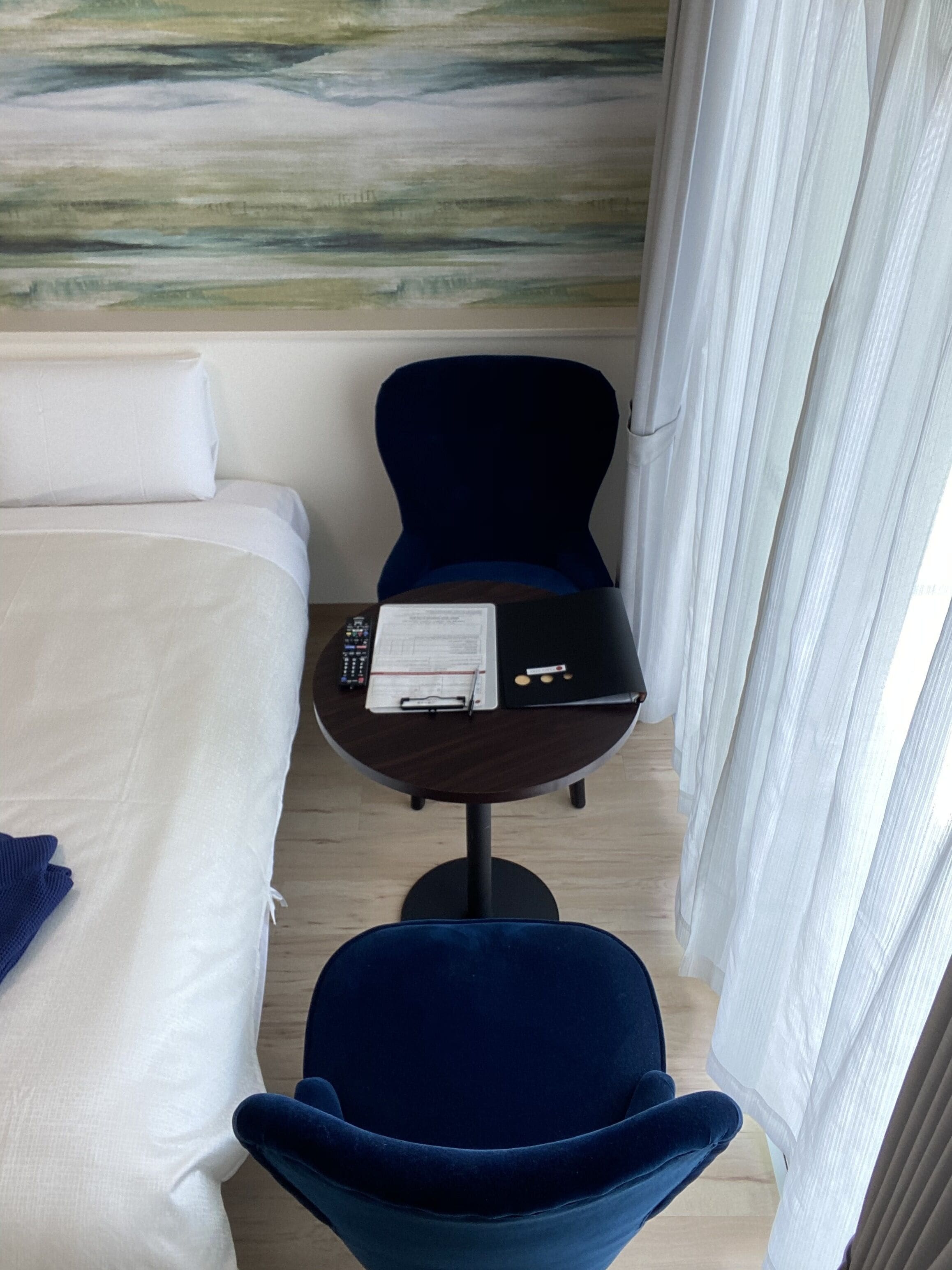 A hotel room with a bed, a desk with a laptop, and a chair.