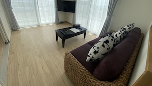 A living room with a sofa, a coffee table, and a TV on a stand. - HOTEL Ishigakijima 2020 (Ishigaki)