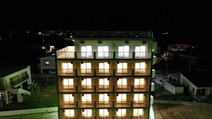 A multi-story building with balconies and large windows, surrounded by other buildings. - HOTEL Ishigakijima 2020 (Ishigaki)