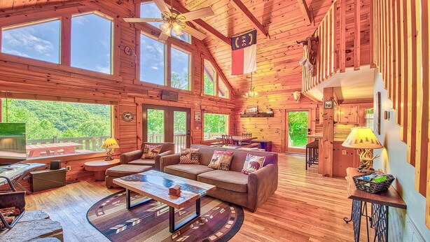 Une cabane en bois spacieuse, dotée d’un grand salon, de nombreuses fenêtres et d’un coin repas.