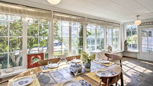 A sunlit dining area with large windows, a table set with plates and glasses, and a decorative vase. - Fire Pit, Views & Beach Access: Waterfront Escape! (University Place)