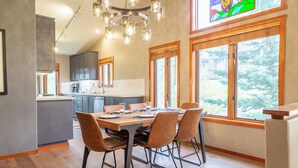 A modern kitchen with a dining area, large windows, and a chandelier. - Luxurious Golf Front Home Mountain Views 479 (Mammoth Lakes)