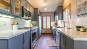 A modern kitchen with grey cabinets, stainless steel appliances, and a large window providing natural light. - Luxurious Golf Front Home Mountain Views 479 (Mammoth Lakes)