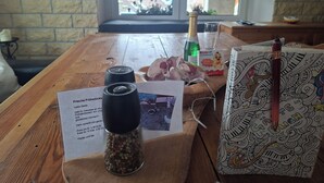 Une table en bois avec une bouteille de champagne, une boîte de chocolats Kinder et un panneau indiquant qu'il y a des en-cas de fruits frais.