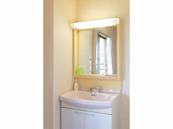 A bathroom with a white sink, a mirror, and a window with curtains.