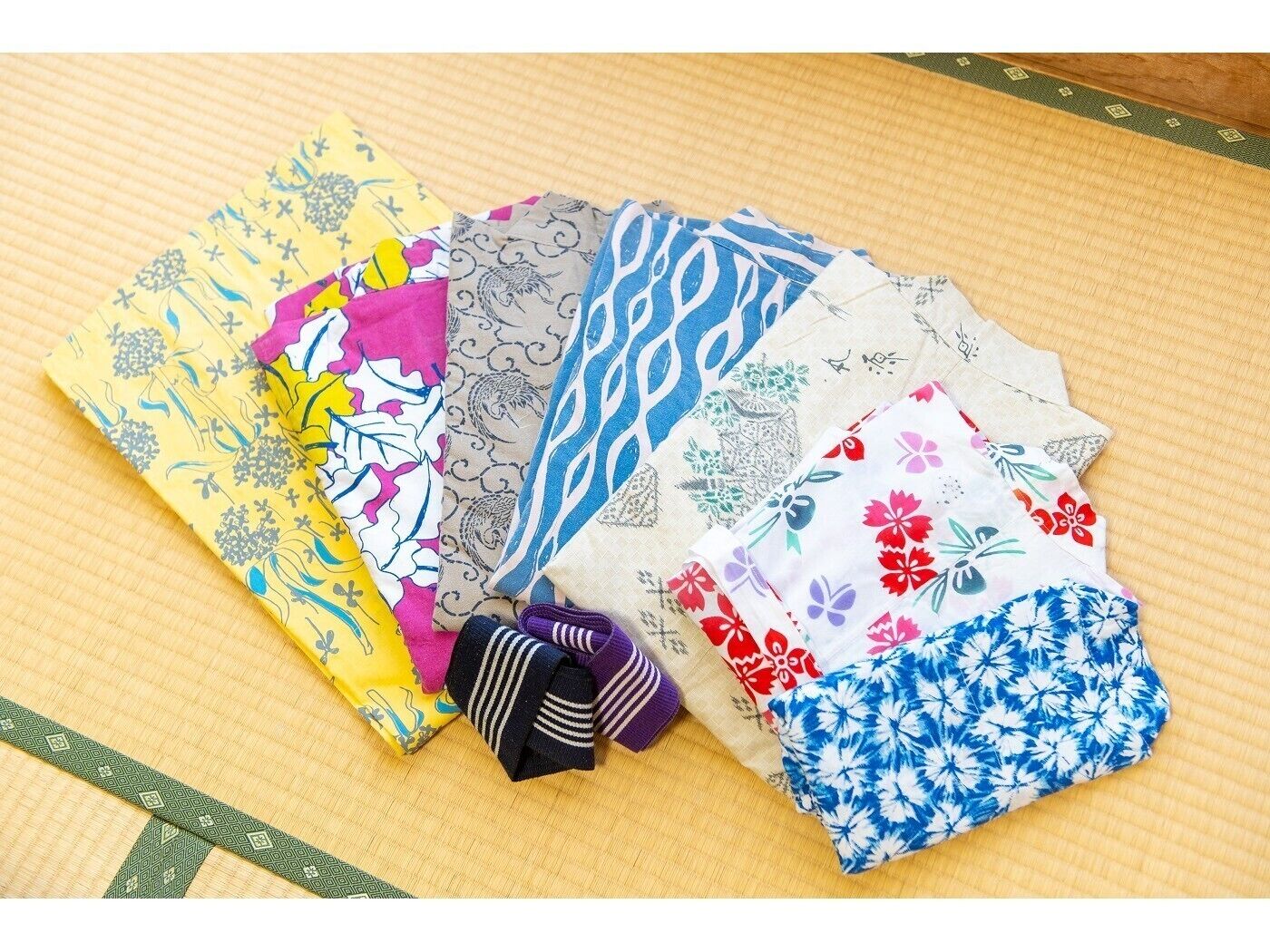 A collection of variously patterned fabrics laid out on a wooden surface.