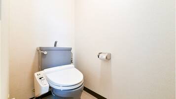 Une petite salle de bain moderne équipée de toilettes, d’un bidet et d’un sèche-mains.