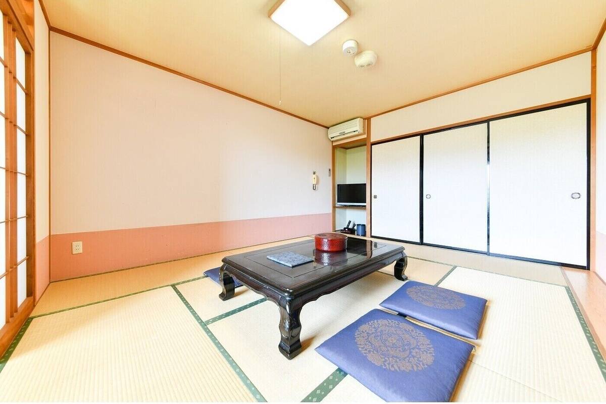 A traditional Japanese room with tatami flooring, a low table, and sliding doors.