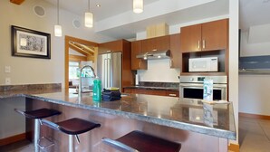 Une cuisine moderne dotée d’un îlot central, d’appareils électroménagers en acier inoxydable et de meubles de rangement en bois.