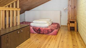 Ein kleines Schlafzimmer im Dachgeschoss mit Holzbalken, einem Etagenbett, einer Holzkommode und einem kleinen Hocker.