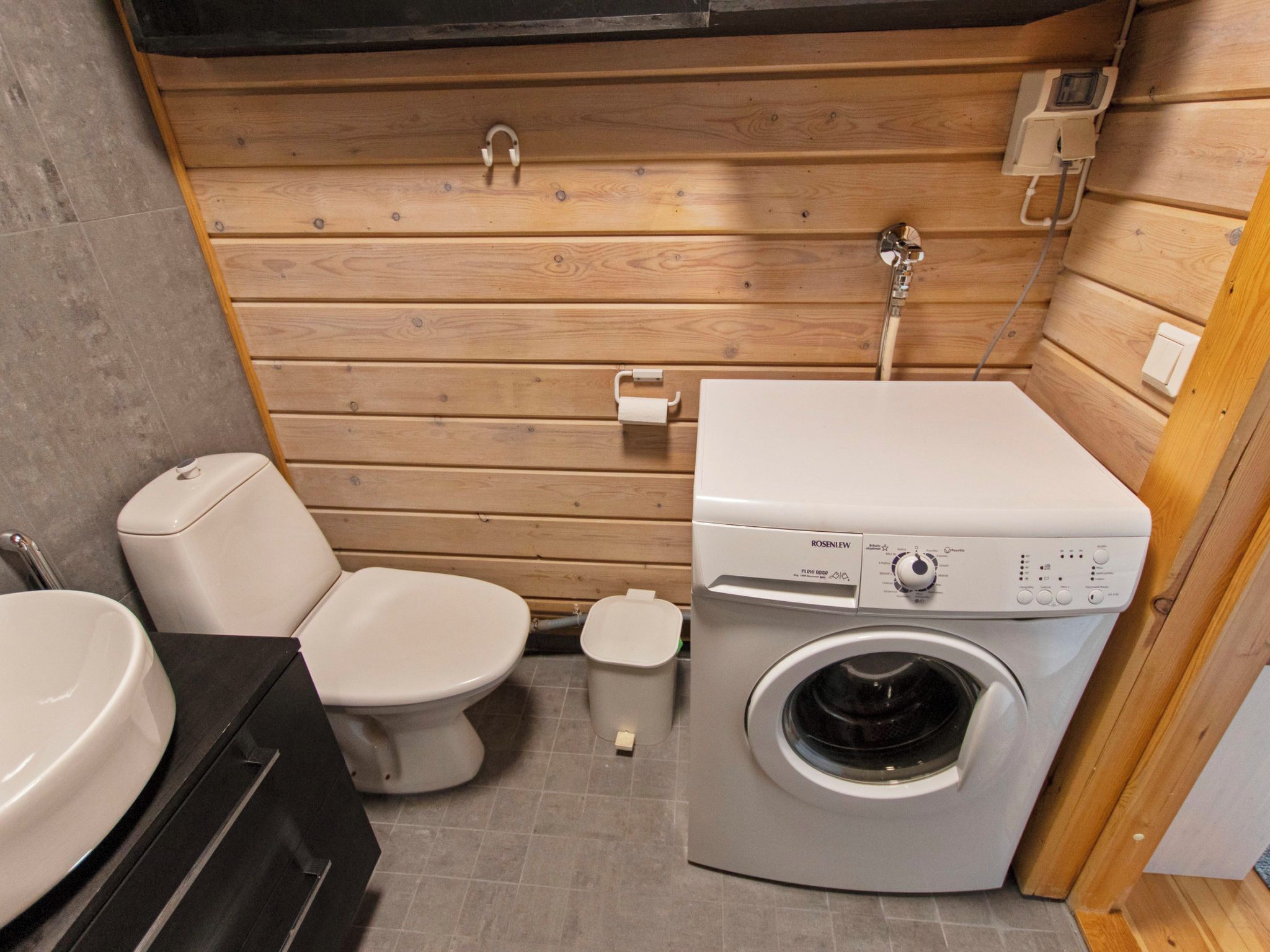 A compact bathroom with a toilet, washing machine, and sink.