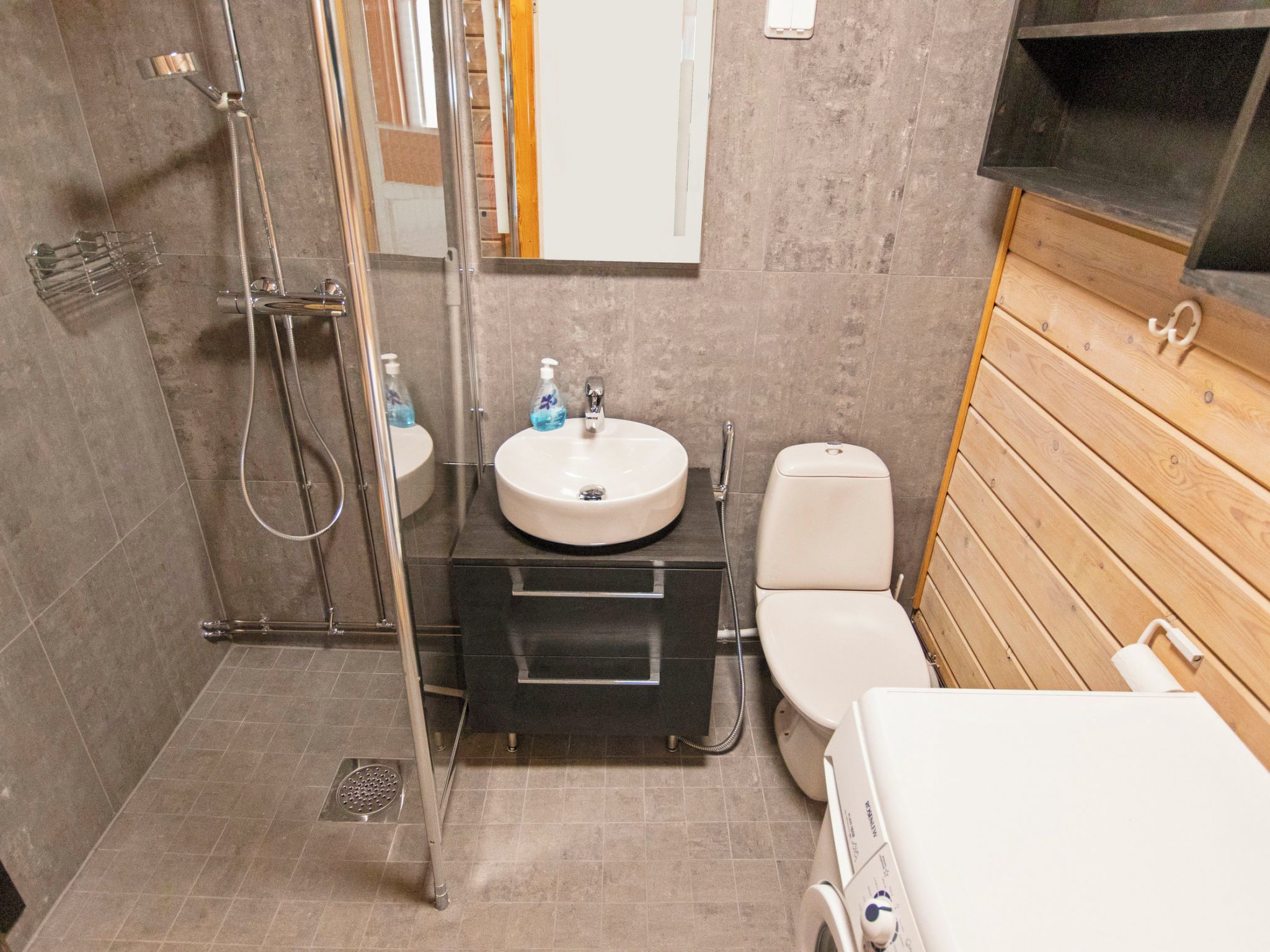 Une petite salle de bain comprenant une douche, un lavabo, des toilettes et un meuble-lavabo en bois.