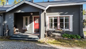 Ein zweistöckiges Haus mit roter Tür und einer Veranda.