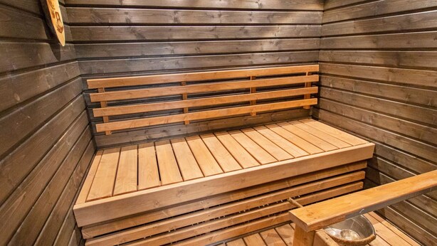 Eine Sauna mit Holzbänken und einer Metallbank.