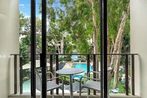 A balcony with a pool view, metal chairs, and a table.