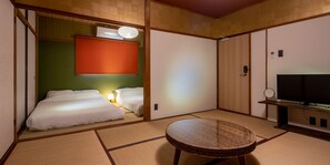 A traditional Japanese room with tatami flooring, a low table, and two beds with white bedding. - SHARE HOTEL 198 Beppu (Beppu)