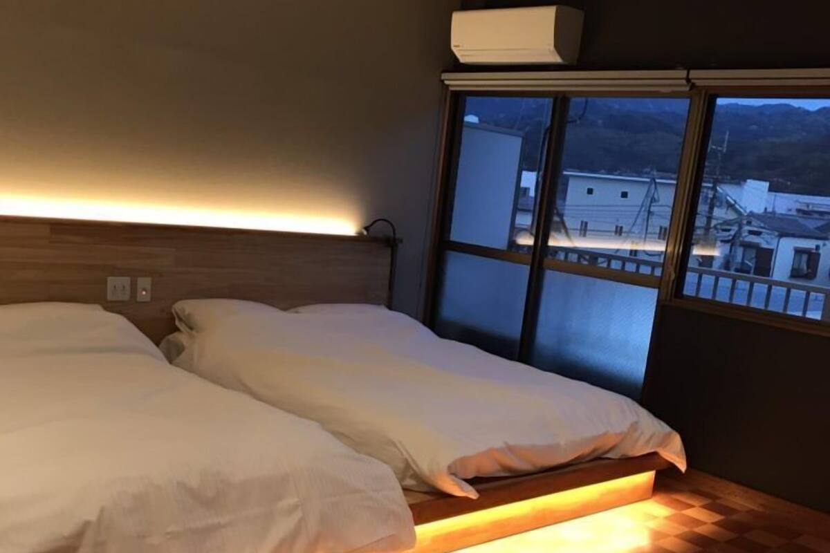 Un dormitorio con cama, ventana y aire acondicionado instalado en la pared.