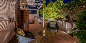A patio area with a seating arrangement including a chair and a table, a small candle, and a view of a building with a glass ceiling. - SHARE HOTEL 198 Beppu (Beppu)