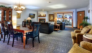A spacious living room with a dining area, a fireplace, and a view into the kitchen. - Ramada by Wyndham Sioux Falls Arpt & Suites (Sioux Falls)