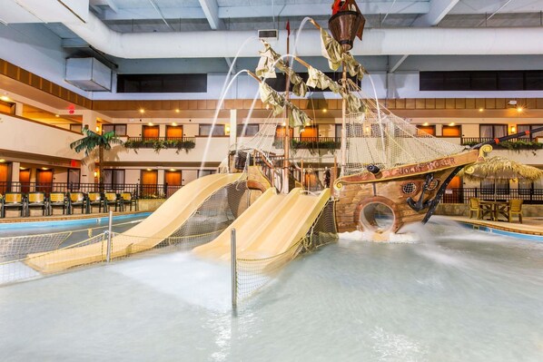 Un parque acuático interior con toboganes y una zona de juegos con temática náutica.