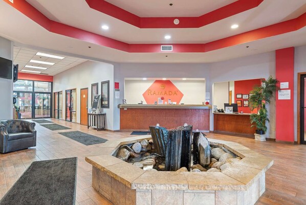 A hotel lobby with a reception desk, a fire pit, and a seating area. - Ramada by Wyndham Sioux Falls Arpt & Suites (Sioux Falls)