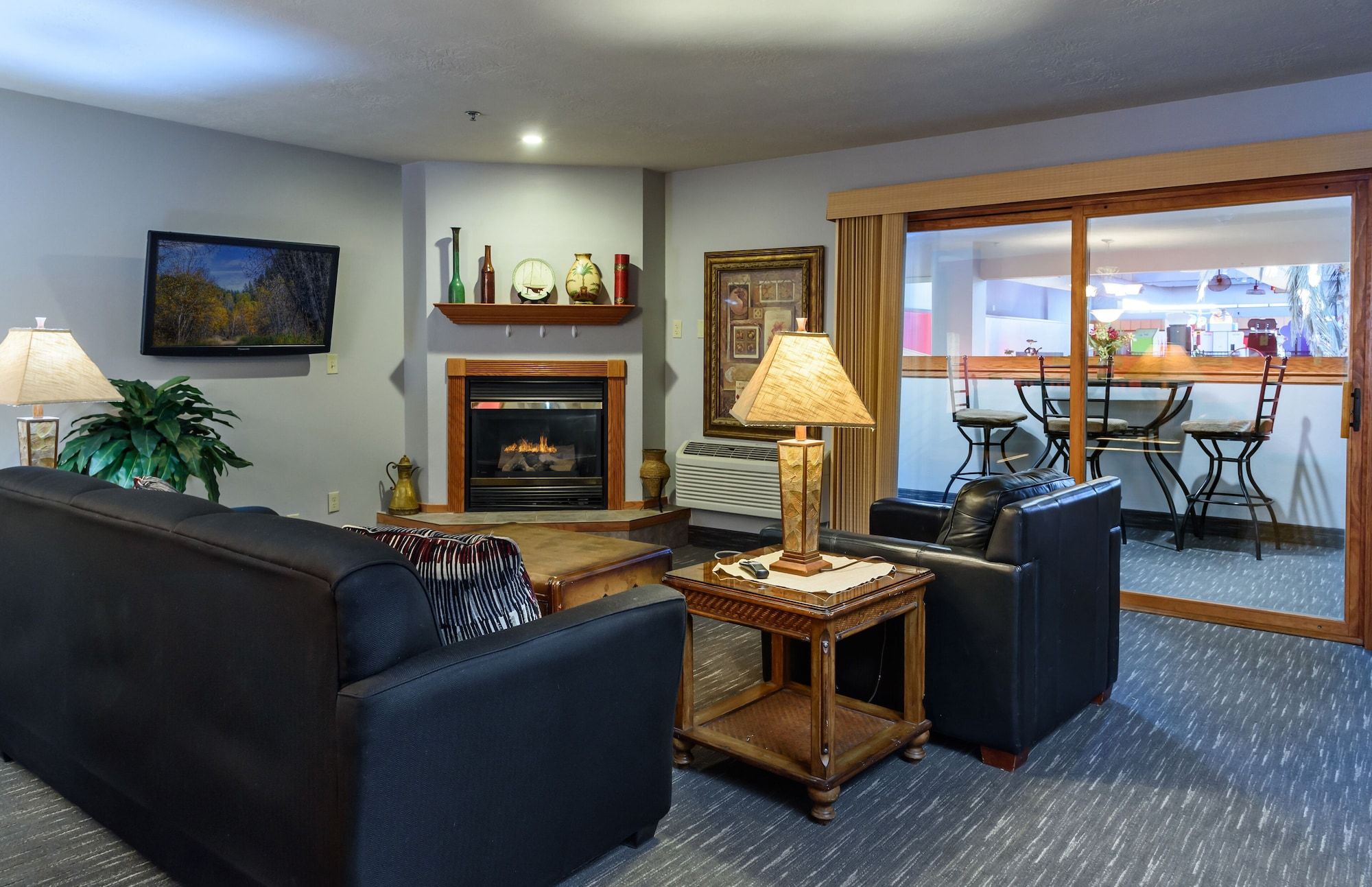 A living room with a fireplace, a sofa, a coffee table, and a dining area visible through a glass door.