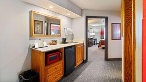 Habitación de hotel compacta con kitchenette, microondas, pileta y un pequeño basurero.