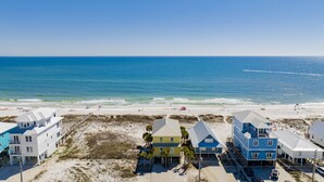 A coastal area with beachfront houses, a sandy beach, and the ocean.