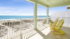 A covered balcony with a view of the beach and ocean.