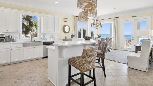 A spacious kitchen with white cabinets, a central island, and a view of the ocean.