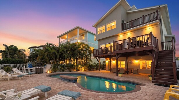 A two-story house with a swimming pool, outdoor seating, and a balcony. - Waterfront Escape—Private Pool, Game Room, Hot Tub & Dockside Views Near Indian Rocks Beach (Indian Rocks Beach)