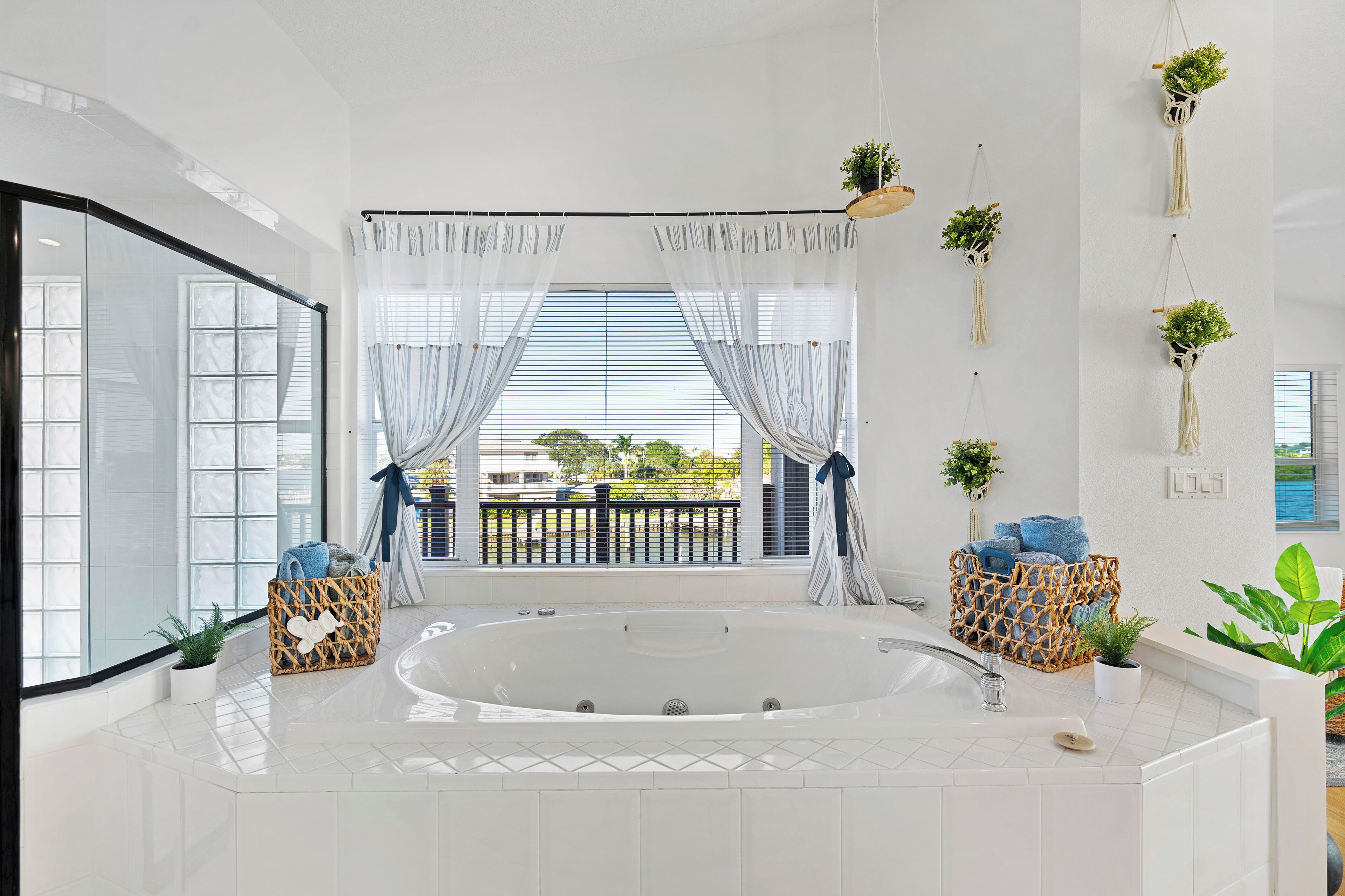 A modern bathroom with a large bathtub, a glass shower enclosure, and a view of the outdoors.