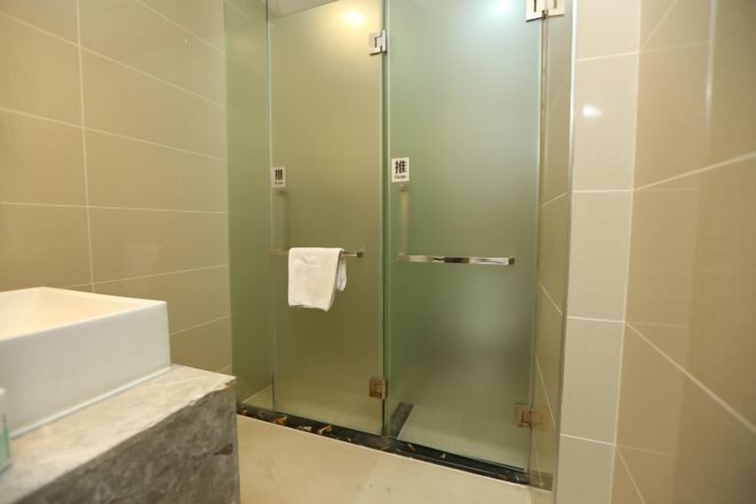 A bathroom with a glass-enclosed shower, a white bathtub, and a marble countertop.