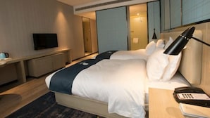 Ein Hotelzimmer mit Bett, Nachttisch, Lampe und Fernseher.