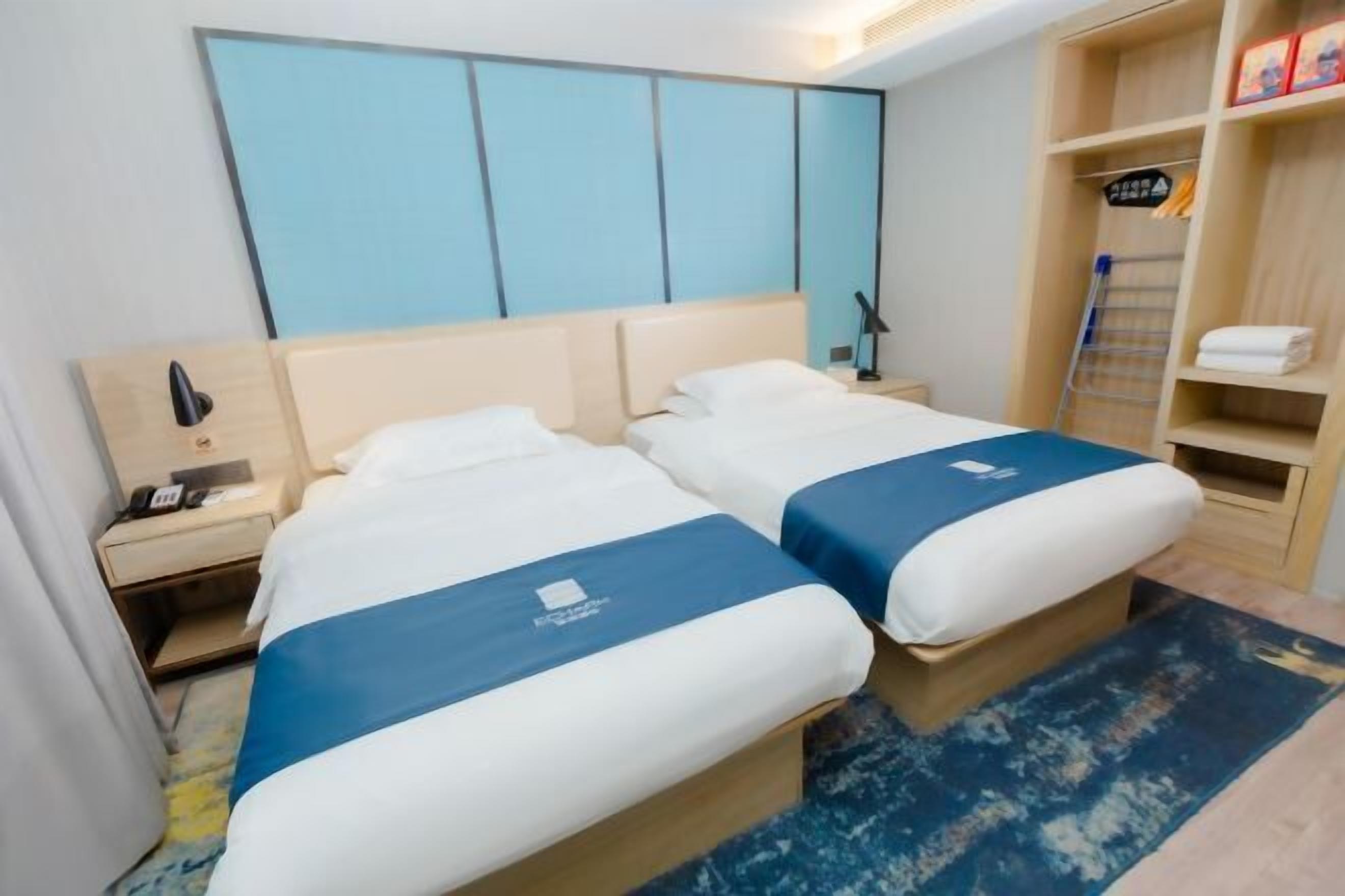Una habitación de hotel con dos camas, un armario, un escritorio y una mesita de noche.