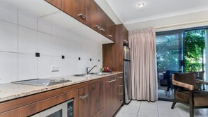 Eine moderne Küche mit einer großen Kochinsel, Edelstahlgeräten und Blick auf einen Balkon mit einem Stuhl.