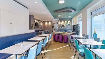 A modern restaurant with a central bar, seating areas, and a kitchen visible in the background.