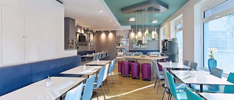 Un restaurante moderno con barra central, zonas de estar y una cocina visible al fondo.
