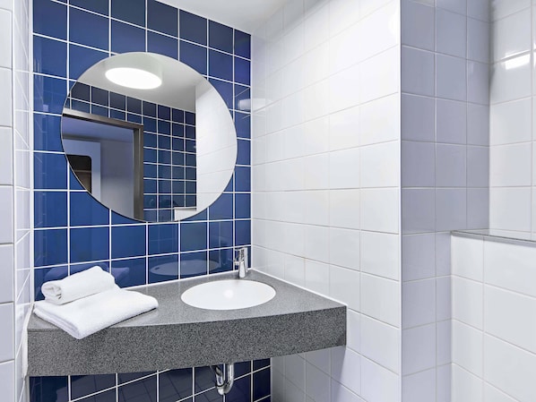 A bathroom with a sink, mirror, and blue tiles.