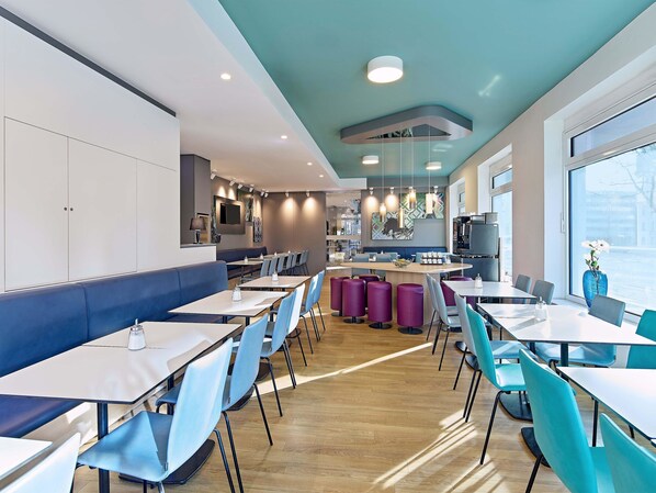 Un restaurante moderno con barra central, zonas de estar y una cocina visible al fondo.