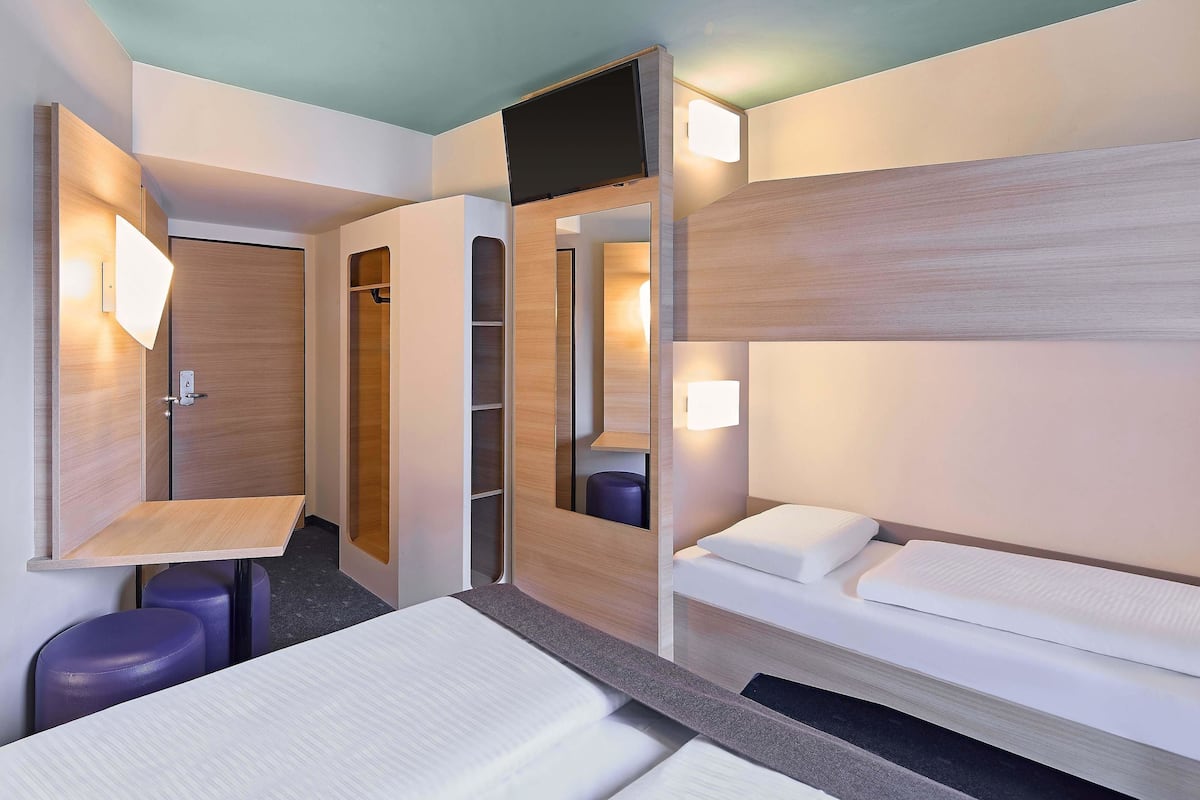 Una habitación de hotel con una cama, un escritorio y un armario.