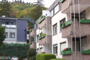 Ein mehrgeschossiges Wohngebäude mit Balkonen, einer Treppe und einem davor geparkten Auto.