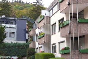 Un immeuble résidentiel à plusieurs étages, doté de balcons, d’un escalier et d’une voiture garée devant.