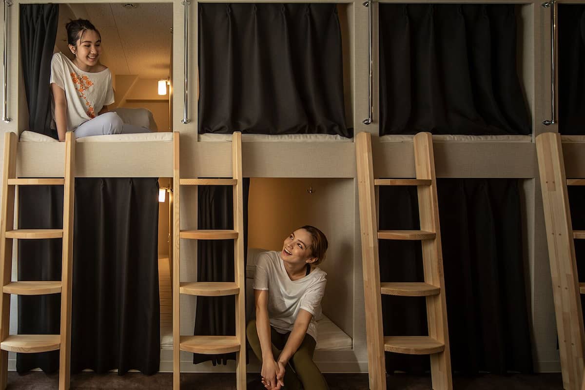 A bunk bed room with wooden ladders and black curtains.