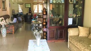 A living room with a sofa, a coffee table, and a cabinet with decorative items. - Poetri Guest House Syariah (Bogor)