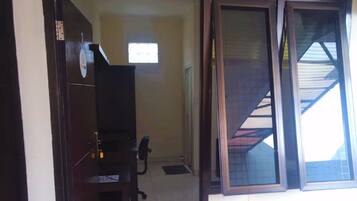A room with a dark wooden wardrobe, a small window, and a door leading to another room.