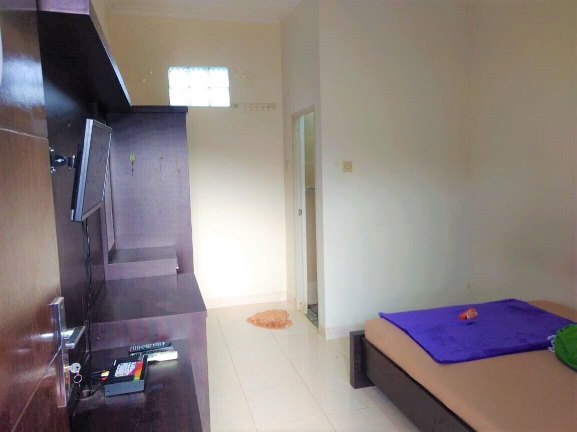 A room with a bed, a desk with a computer, and a window.