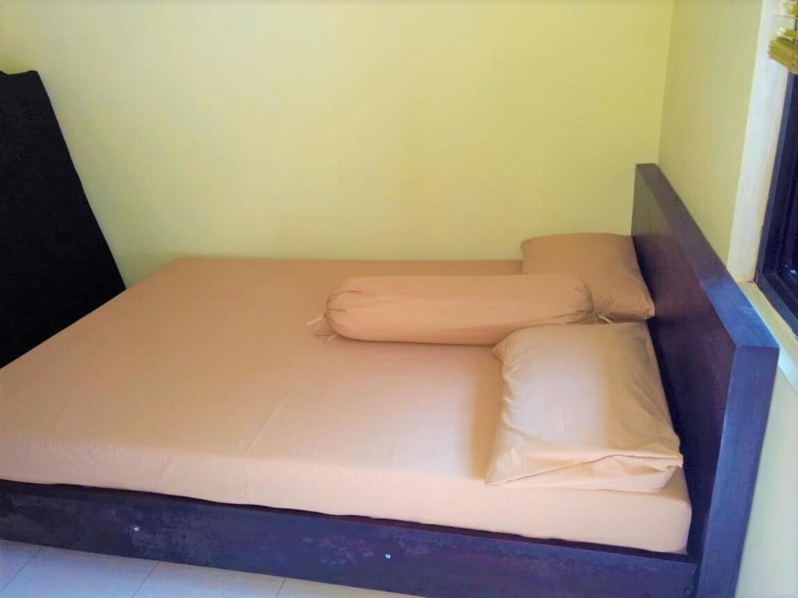 A bed with a dark headboard and a light-colored mattress.