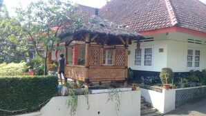 A traditional house with a thatched-roof structure in front, a white exterior, and a red-tiled roof. - Poetri Guest House Syariah (Bogor)